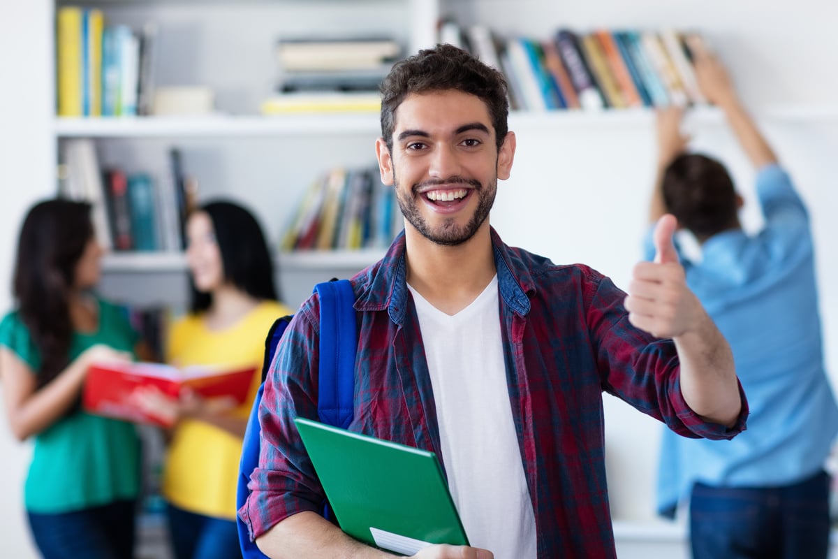 Happy spanish male student with group of students